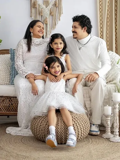 A candid moment of laughter during a family photoshoot. The all-white theme and boho decor create a light and joyful atmosphere.