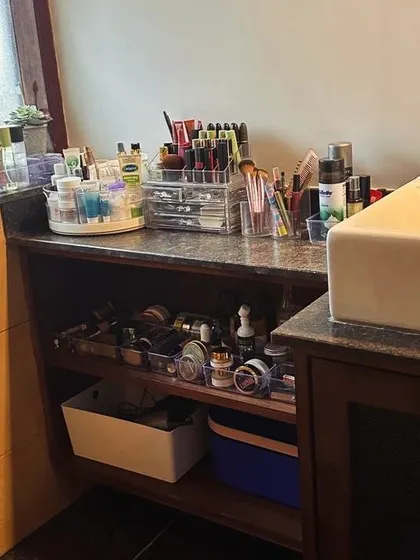 An organized vanity counter in a bathroom. Using clear acrylic organizers and a turntable for daily items keeps the counter tidy and makes your routine efficient.