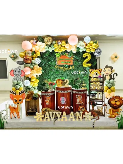 A jungle theme for Avyaan's second birthday, with a green hedge backdrop and cute animal props.