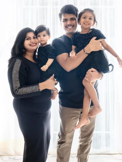 A beautiful studio portrait of a family of four. The parents each hold a daughter, showcasing the family's unity and love in a classic composition.