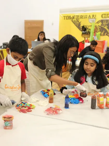 I'm helping two children with a colorful tie-dye project during a birthday party, ensuring everyone has a fun and creative time.