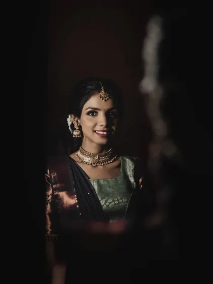 A creative shot peeking through a dark space. The makeup and smile still shine through.