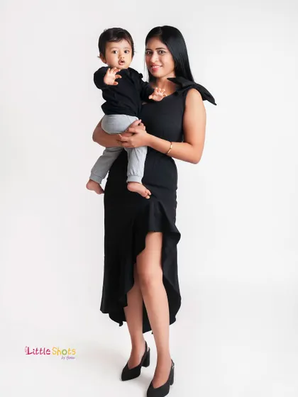 A stylish mother and son portrait. Their matching black outfits and the mother's loving hold create a chic and heartwarming image.