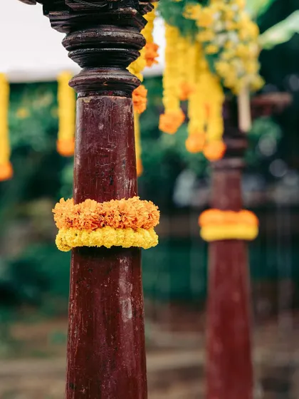 A detail shot of a traditional pillar wrapped in orange and yellow marigolds, showcasing the simple yet effective use of color.
