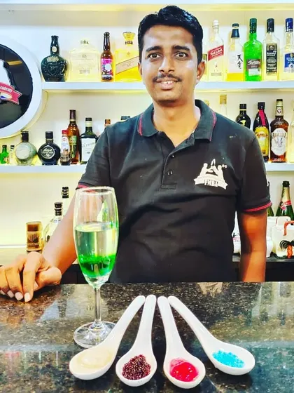 A student displays his creations from the molecular mixology class, including colorful caviars and a layered drink.
