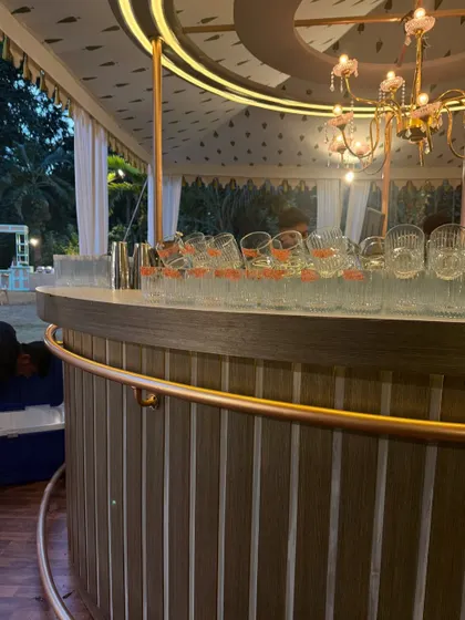 The bar is ready for the S+V wedding dinner party. The custom circular bar with elegant lighting and glassware awaits guests for an evening of celebration.
