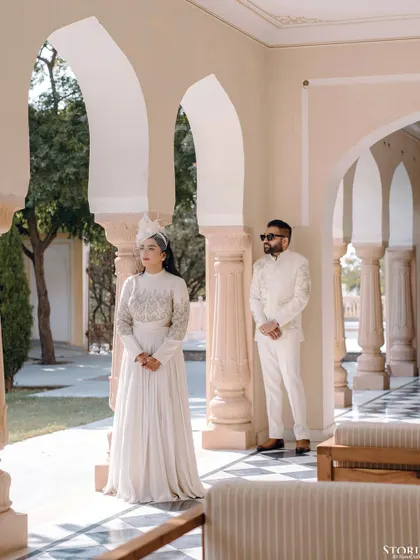 A beautifully composed shot of the couple in a palace corridor, using the pillars and arches to create a sense of depth and grandeur.