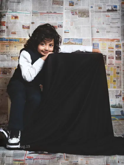 A sweet and gentle pose from a five-year-old boy, resting his head on a black pedestal.