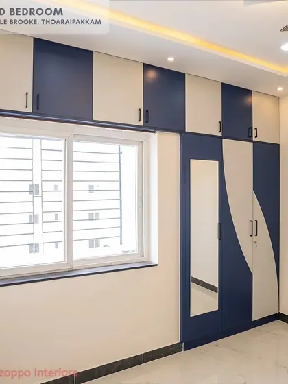 A bedroom in Jain's Pebble Brooke with a striking wardrobe design, using a dynamic wave pattern in dark blue and cream across the shutters.