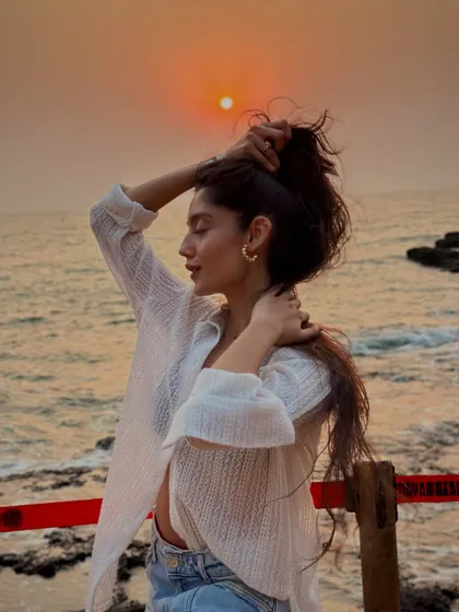 Tying up my hair against the backdrop of a golden sunset. A classic beach moment that captures the carefree spirit of our travels.