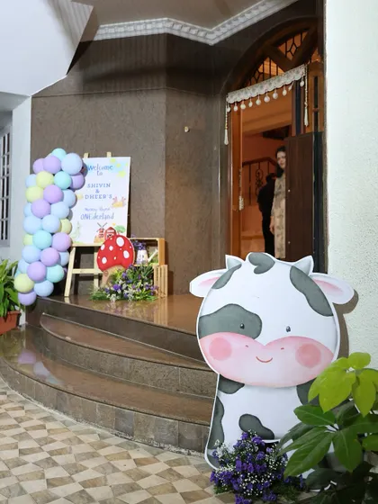 A cute cow cutout stands at the entrance of the party, welcoming little guests to the nursery rhyme adventure.