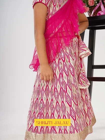 A close-up of the details on this pink and gold printed lehenga. The pre-draped ruffled dupatta adds a contemporary flair that little girls absolutely adore.