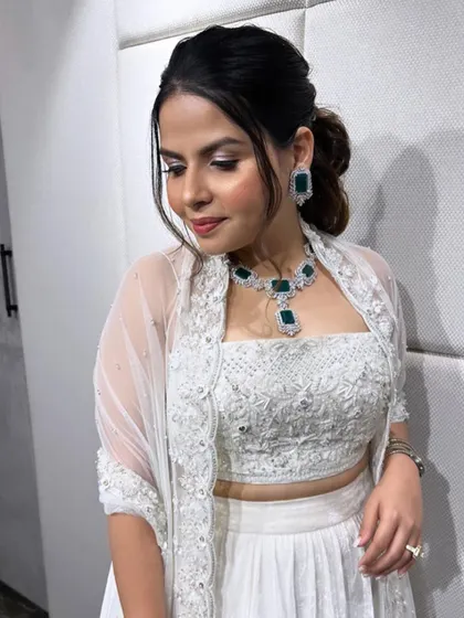 The bride looks effortlessly chic with her messy ponytail and statement emerald jewelry.