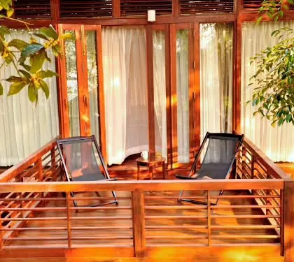 The private wooden balcony of a nature lodge in Coorg. This is the perfect spot to enjoy your morning coffee while listening to the sounds of the forest and watching the mist roll over the hills.
