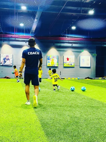 A coach watches over his young players, a proud mentor guiding the next generation of football talent.