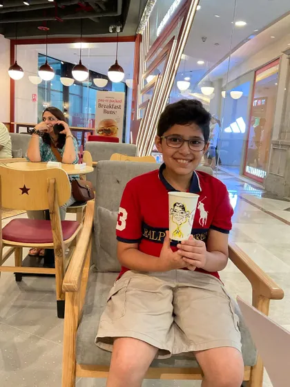 A young customer at Pret A Manger, happy with his caricature drawn right on the coffee cup.