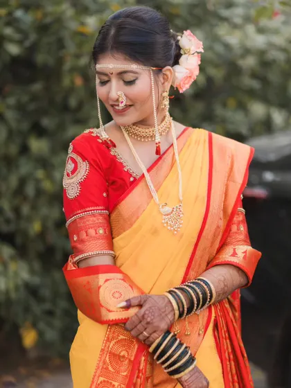 The bride looking down with a gentle smile, a simple and elegant pose that highlights the details of her embroidered blouse and saree.