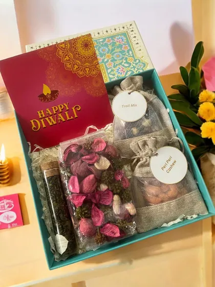 A refreshing green-themed Diwali hamper containing healthy green tea, fragrant potpourri, and small jute bags of trail mix and peri-peri cashews.