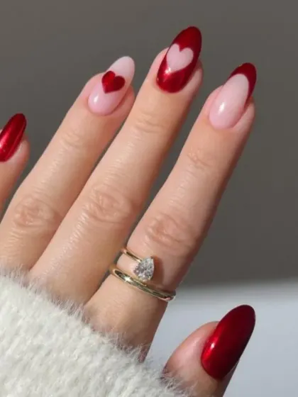 A lovely heart-themed French manicure. This design combines classic red tips with accent nails featuring heart cutouts and heart paintings on a natural pink base.