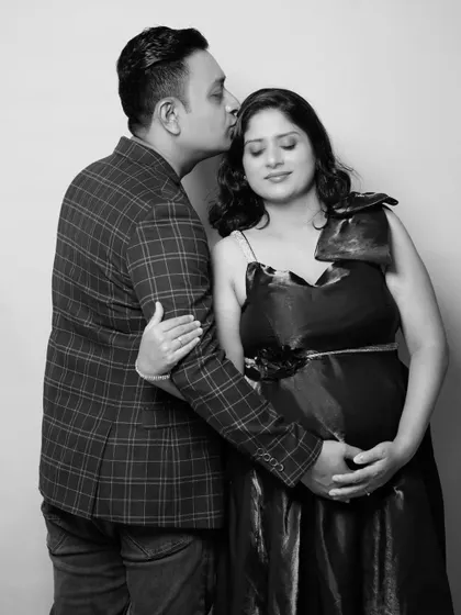 An intimate black and white photo of a partner kissing the mother-to-be's forehead. This pose emphasizes their close bond and the gentle emotions of this special time.