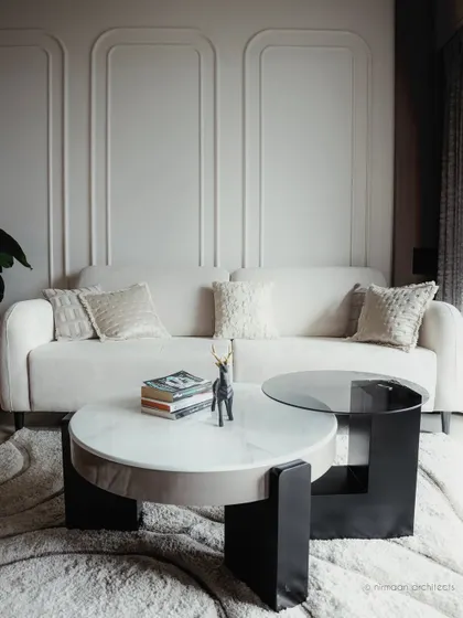 A detail shot of the living room at Sai World Empire, focusing on the elegant white sofa and modern coffee table. The wall molding adds a classic touch to the contemporary design.