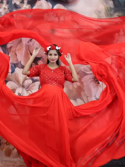 A vibrant maternity photo with the mother-to-be in a flowing red gown, creating a heart shape with the fabric.