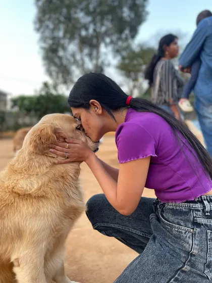 A visitor gives a gentle kiss to the top of a Golden Retriever's head, a perfect picture of love.