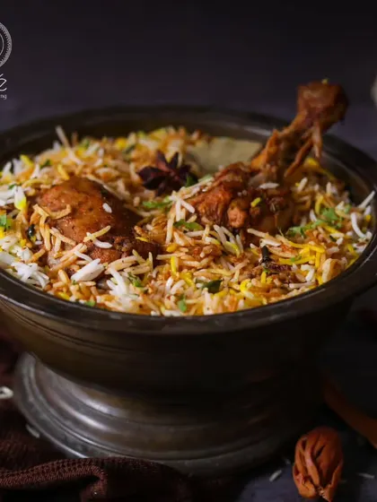 A rich and aromatic chicken biryani, served in a traditional bowl. This classic dish is a staple of our Indian cuisine offerings, slow-cooked with fragrant spices.