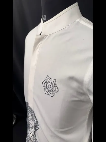 A side view of the abstract-figurative white shirt, showing the placement of the small geometric floral motif on the chest.