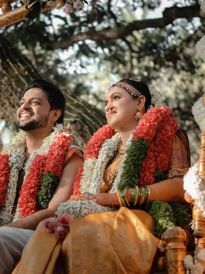 A candid moment of the couple sharing a smile while seated on a traditional wedding swing. The natural light and joyful expressions make this a cherished memory.