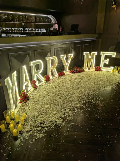 A detailed close-up of the illuminated letters and the texture of the faux grass and rose petals. Every element is chosen to contribute to the overall look and feel.