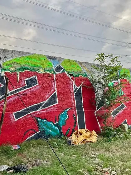 Another angle of the 'शुभ' piece, showing how it interacts with the broken wall and surrounding nature.
