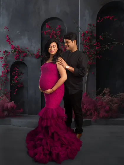 A beautiful couple's shot against a modern, textured backdrop with pops of magenta flowers. The image captures the love and partnership of the journey into parenthood.
