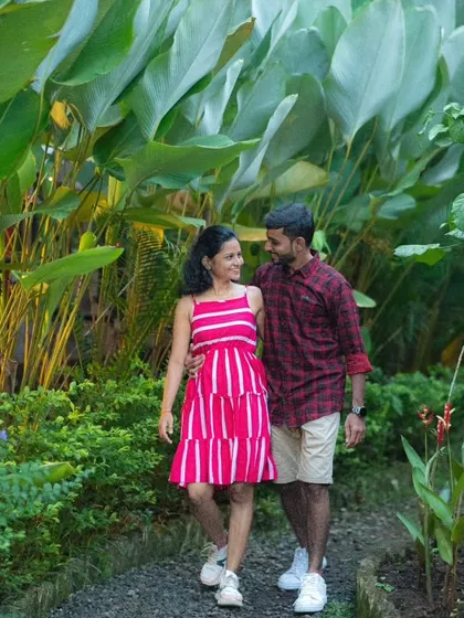 A couple enjoys a romantic walk through a botanical garden, their colorful outfits complementing the lush green surroundings in this pre-wedding photo.