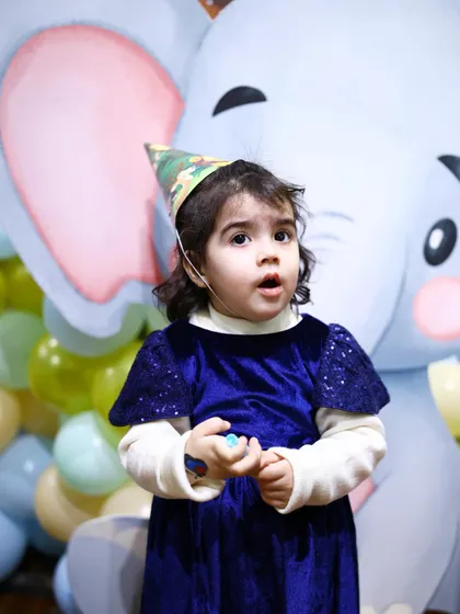 The birthday girl, wearing a cute safari hat, looks on with wonder at her jungle-themed party. We love seeing the children's reactions to our immersive decor.