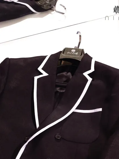 Our modern black double-breasted blazer features a striking white piped edge. This sharp detail elevates the classic design, making it perfect for high-impact occasions.