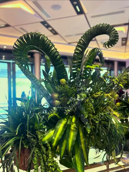 A garden of sweetness. This dessert table features whimsical, dinosaur-like sculptures made of curled palm fronds, surrounded by an abundance of sweets and treats.
