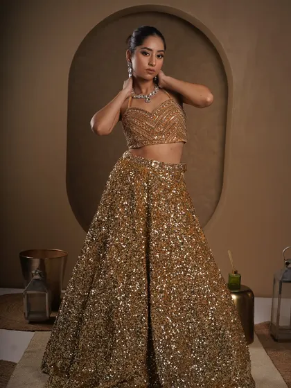 A full-length view of a stunning golden sequin lehenga. The studio lighting is set to make every sequin sparkle, creating a look of pure opulence for a wedding or reception outfit.