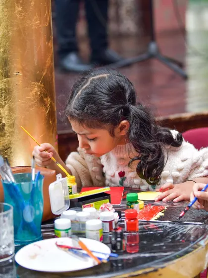 A young artist completely absorbed in her painting. I provide all the supplies for kids to create their masterpieces during brunch, offering a perfect blend of artistic fun and family dining.