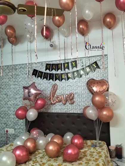 A classic anniversary room decoration. We fill the ceiling with balloons, scatter them on the bed, and add a 'Happy Anniversary' banner and 'love' foil balloon for a sweet surprise.