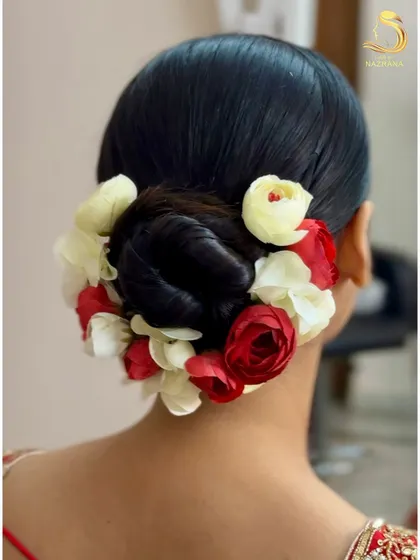 A clean, sleek bridal bun adorned with a mix of red and white flowers for a classic look.