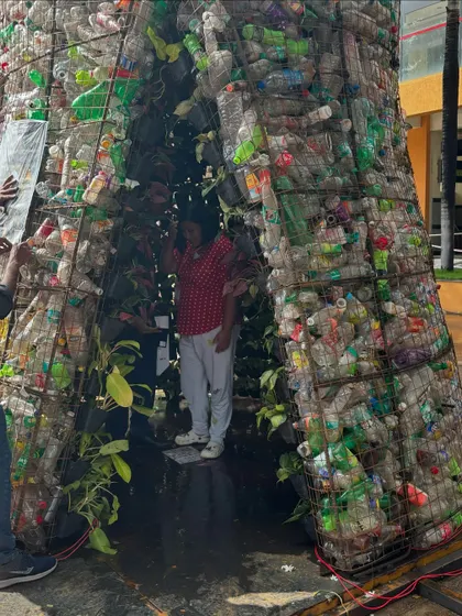 A view of the entrance to the "Plastreen" installation, showing the structure made from a wire mesh cage filled with used plastic bottles.