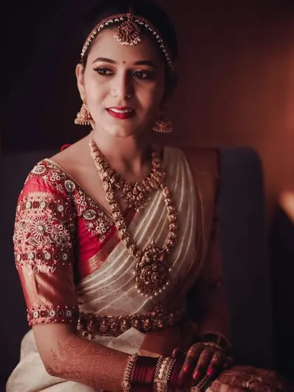 A portrait of elegance. This close-up shot highlights the detailed handwork on the sleeves of her custom bridal blouse, designed to match her traditional temple jewelry.
