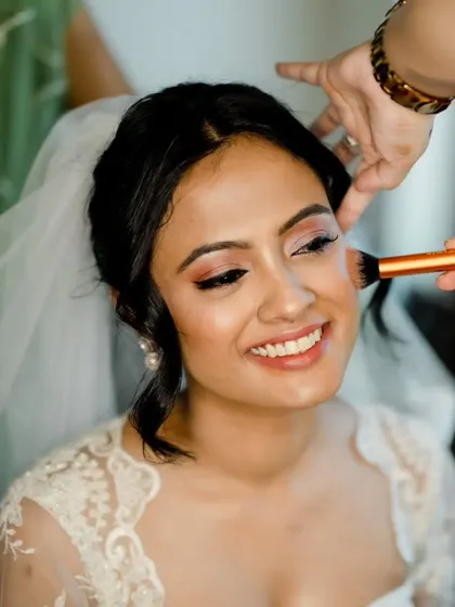 The joy on a bride's face when she sees her final look is priceless. Here, I'm applying a touch of blush to give her that perfect, happy glow.