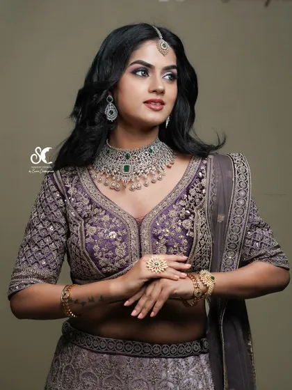 A model showcasing a Royal North Indian bridal look for a makeup artist's portfolio. The lighting is carefully controlled to accentuate the rich details of the embroidered lehenga and jewelry.