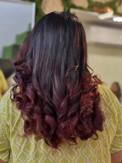 A bold and beautiful red balayage. The color is concentrated on the mid-lengths and ends, creating a dramatic and stylish effect on her dark hair.