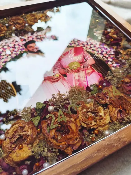 A close-up look at the glossy finish and intricate details of a 14x14 inch teakwood varmala preservation frame, showing the preserved flowers and pearl elements.