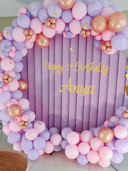 The circular velvet backdrop is the star of this butterfly-themed setup, framed perfectly by pink, purple, and rose gold balloons.