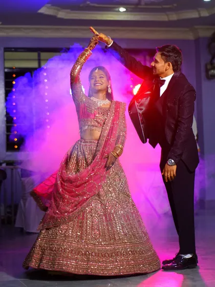 A couple shares their first dance, surrounded by theatrical smoke and colorful lights. I work to create dramatic, memorable images from the most important parts of your reception.