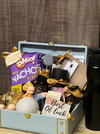 A full view of the contents of a farewell hamper, including a water bottle, snacks, and other curated items in a reusable suitcase box.